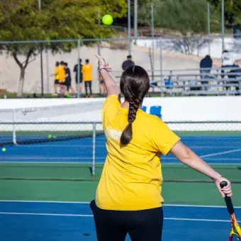 Alumna preparando saque de tennis. 