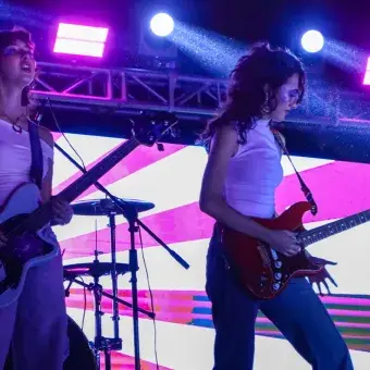 Dos chicas tocando el bajo y la guitarra en el escenario.