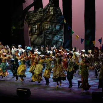 Bailan en el escenario actores y bailarines de Cenicienta.